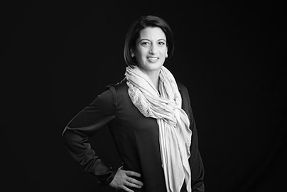 Black and white portrait of a woman with short dark hair, wearing a long-sleeve blouse and light-colored scarf, standing with one hand on her hip and smiling—an ideal choice for professional headshots or branding in Calgary. - Jodi O Photography