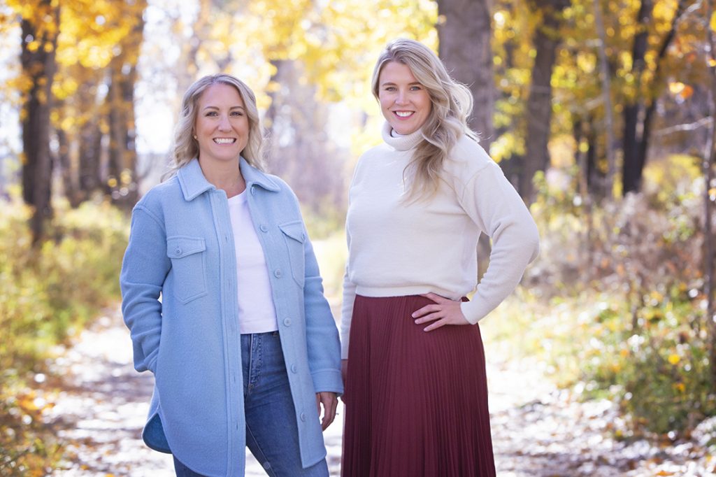 Outdoor fall headshot session for a professional team in Fish creek Calgary. 2 young women smile with golden leaves around them.