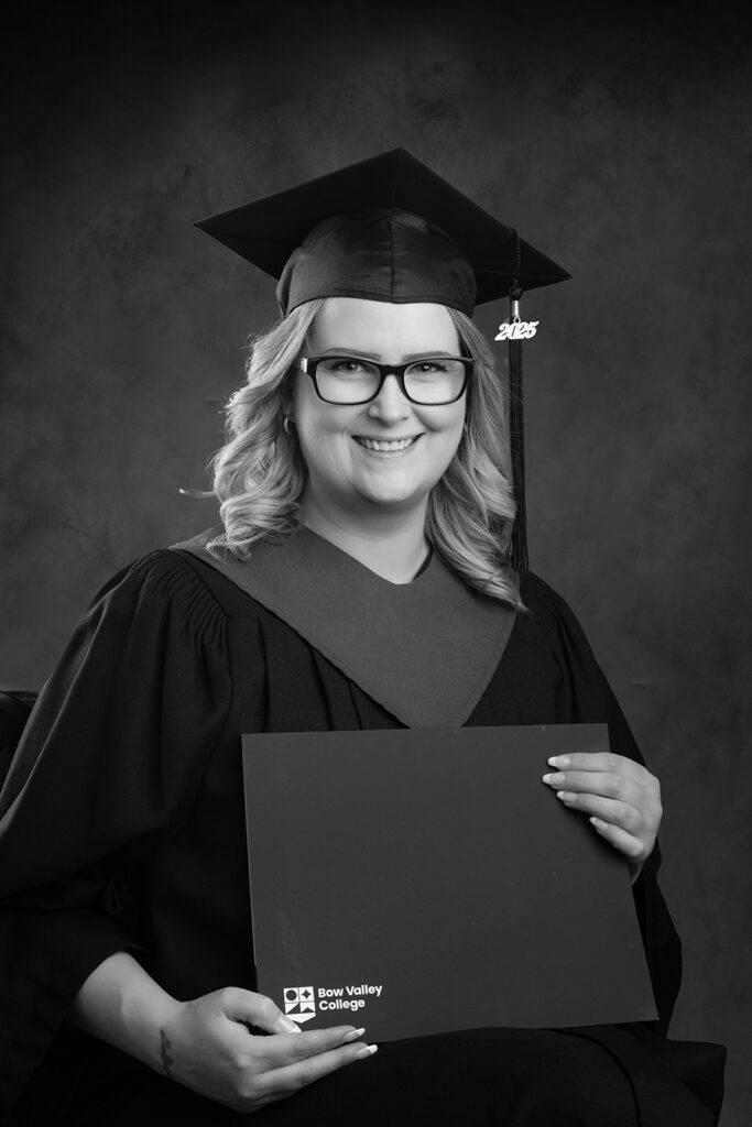Black cap and gown worn by Calgary woman with her graduation certificate